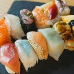 A colorful assortment of sushi varieties beautifully arranged on a black slate platter, highlighting Japanese cuisine.