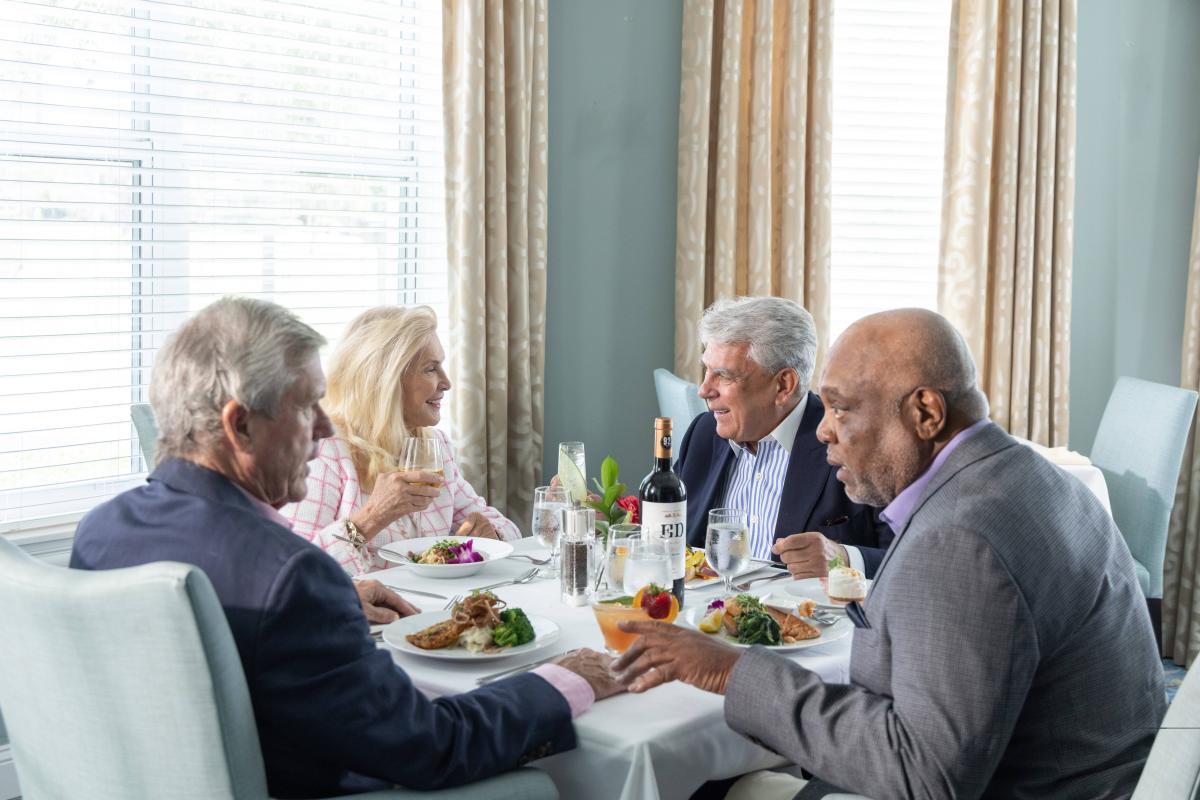 four people eating dinner and drinking wine